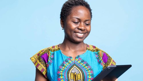 african-american-girl-is-pleased-use-tablet-against-blue-backdrop