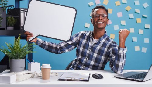 marketing-company-happy-smiling-young-adult-person-holding-bubble-sign-while-clenching-fist-triumphant-management-department-team-leader-with-cardboard-speech-bubble-work